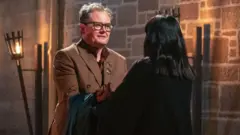 Alan Carr receiving his Traitors cloak from Claudia Winkleman