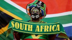 A woman wears South African football colours and the national flag.