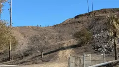 Workers are seen on the ridge line in the Temescal Canyon burn area