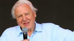 Sir David Attenborough holding a microphone on stage at Glastonbury Festival