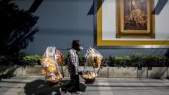 A food vendor walks past a portrait of Thai King Maha Vajiralongkorn Bodindradebayavarangkun in Bangkok
