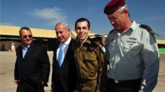 In this handout photo provided by the Israeli Defense Force, freed Israeli soldier Gilad Shalit (2nd R) walks with Defence Minister Ehud Barak (L), Israeli Prime Minister Benjamin Netanyahu (2nd, L) and IDF Chief of General Staff Benny Gantz (R) at Tel Nof Airbase on 18 October 2011 in central Israel
