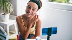 Una joven maquillándose frente a un celular.