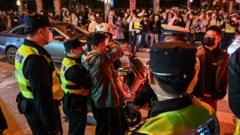 Police officers confront a man amid crowded scenes at a road junction in Shanghai