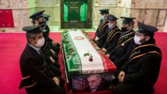 Mourners sit next to the coffin of Iranian nuclear scientist Mohsen Fakhrizadeh