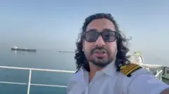 Captain Raman Kapoor on board his ship with the Strait of Hormuz in the background