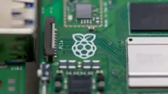 A close up of a Raspberry Pi computer with the white logo of a raspberry