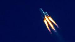 rocket flying diagonally with flames in front of dark blue sky