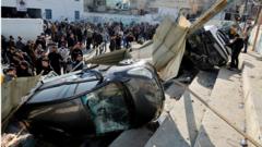 Palestinians inspect damaged vehicles and buildings in Jenin, in the occupied West Bank, after nine Palestinians were killed in an Israeli military raid (26 January 2023)