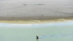 A fisherman tries to find fish in the shallow waters of the dried-out Puzhal reservoir on the outskirts of Chennai, June 2019