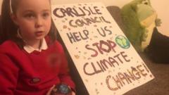 Emily with a sign which says Carlisle council help us stop climate change