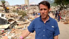Man in blue shirt walking among rubble after earthquake
