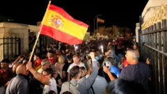 A large crowd crosses the border between Gibraltar and Spain as one person holds up a Spanish flag