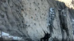 Elio Della Ferrera, Arch. PaleoStelvio Two people look up at the wall of footprints