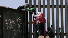 A small boy is passed over a border wall in the US.