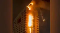 A high-rise building engulfed in flames in Kuwait City.