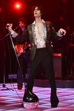PA Media Sombre performing on The Graham Norton Show in November 2025 in a half-open white shirt and black jacket with decorative embroidery, leaning on a microphone stand with one hand.