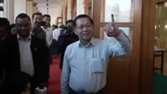 Win Kyaw Thu/BBC Myanmar junta chief Min Aung Hlaing holds up his ink-stained finger outside a polling station.