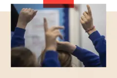 PA Wire School children in a classroom raise their hands up