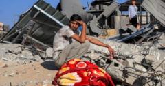 A Palestinian youth sits by the rubble of a building following an Israeli air strike in Rafah in the southern Gaza Strip on October 13, 2023