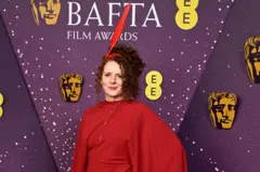 Getty Images Maggie O'Farrell in a red dress with a red quill headpiece