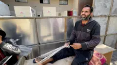 Said Barcat holds an improvised covering around the bare foot when he sits on a wooden bench near the MSF clinic