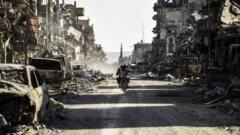 A Syrian youth uses his cell phone to film the destroyed vehicles and heavily damaged buildings down a street in Raqqa on October 20, 2017