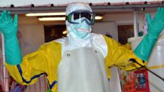 A health worker wearing protective gear is sprayed with disinfectant at the Nongo Ebola treatment centre in Conakry, Guinea, on August 21, 2015