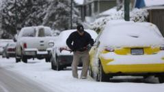 A man wipes snow off his car