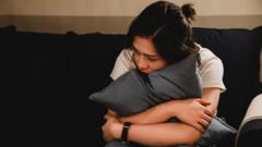 Young woman hugs a cushion and looks anxious