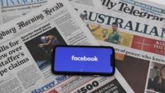 A phone showing the Facebook logo on a spread of Australian newspapers