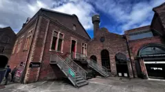 The brick boiler house in front of a large tower against a blue sky
