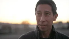 A head shot of Geoffrey Koo with the sun setting behind him. He has short dark hair and is wearing a dark colored jacket.