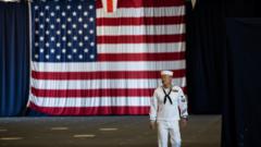 美国纽约美军巴丹号航母上一名海军士兵在一面举行美国国旗前走过（30/5/2022）
