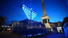 James Manning/PA Wire A large menorah lit-up in neon lights stands in Trafalgar Square, in front of Nelson's Column, as night falls