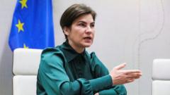 Iryna Venediktova sentada e falando em sala de reunião