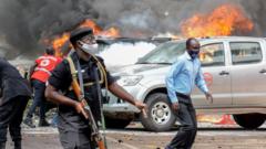 People extinguish fire on cars caused by a bomb explosion near Parliament building in Kampala, Uganda, on November 16, 2021.