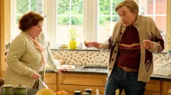 Alan Partridge in his kitchen talking to his assistant, Lynn Benfiel (Felicity Jane Montagu)