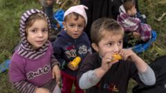 Three Syrian children in Hungary, one of them eating raw corn