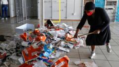 Local woman uses broom to sweep mess inside looted store