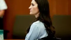 Side profile of Lindsay Clancy who has long dark hair and is wearing a light blue long-sleeved top.