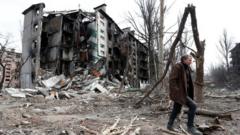 Man walks near residential building in Mariupol