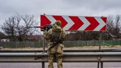 A soldier looks down his scope down towards the highway near Sytnyaky, Ukraine