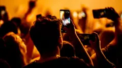 Getty Images A crowd is filming a concert on their phones