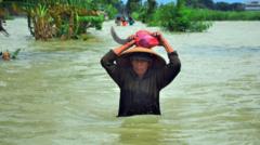 Warga melewati jalan yang tergenang banjir di Karangturi, Setrokalangan, Kudus, Jawa Tengah, Selasa (03/01)