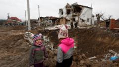 Kids stand next to a crater left by a Russian military strike in the town of Hlevakha, outside Kyiv