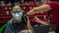 A healthcare worker administers a dose of Sinovac Biotech's CoronaVac vaccine to a woman at a mall theatre converted into a vaccination centre on June 1, 2021 in San Juan, Metro Manila, Philippines