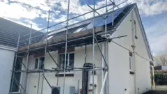 A house with scaffolding, solar panels and a heat pump