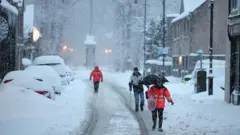 Getty Images People walk on the streets during snowfall in Huntly, Scotland.