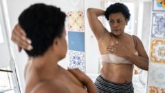 Una mujer se mira al espejo mientras inspecciona sus mamas.
